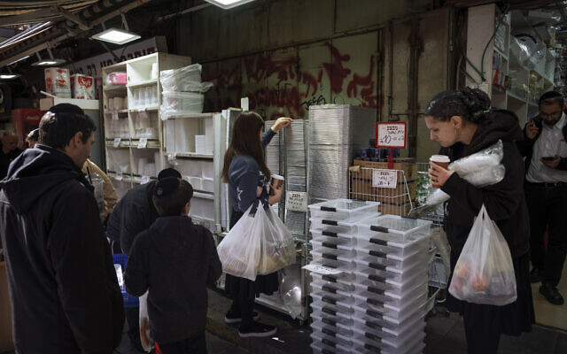 People buy disposable plastic dishes at Mahane Yehuda market in Jerusalem, January 20, 2023. (Oded Balilty/AP) People buy disposable plastic dishes at Mahane Yehuda market in Jerusalem, January 20, 2023. (Oded Balilty/AP)