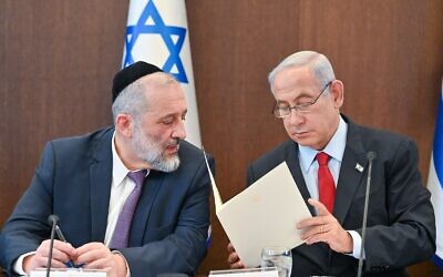 Prime Minister Benjamin Netanyahu (right) reads a letter to Shas chair Aryeh Deri, informing Deri that he must remove him from ministerial office, at the weekly cabinet meeting in Jerusalem, January 22, 2023. (Kobi Gideon/GPO)
