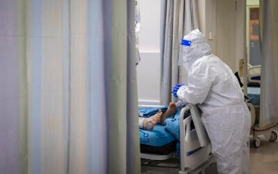 Illustrative: A medical worker at Hadassah Hospital Ein Kerem in Jerusalem treats a patient in the coronavirus ward on December 27, 2021. (Olivier Fitoussi/Flash90)
