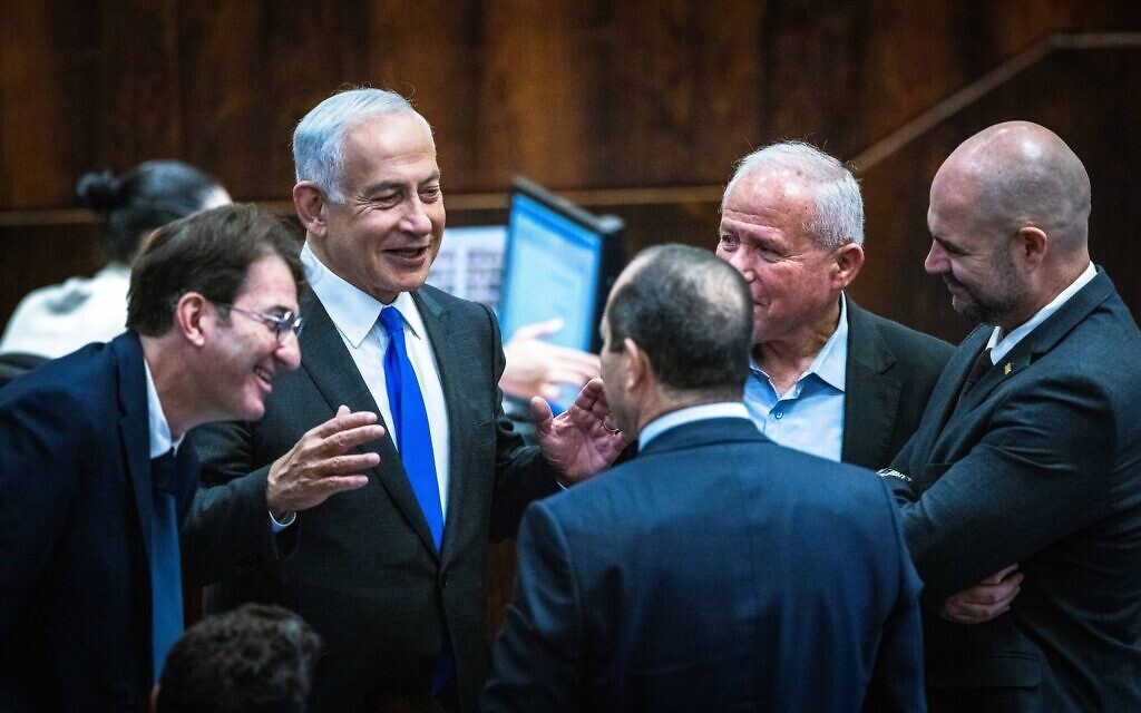 Benjamin Netanyahu speaks with other Likud MKs including Nir Barkat (back to camera) and Avi Dichter (right) in the Knesset plenum on December 28, 2022. (Olivier Fitoussi/Flash90) Benjamin Netanyahu speaks with other Likud MKs including Nir Barkat (back to camera) and Avi Dichter (right) in the Knesset plenum on December 28, 2022. (Olivier Fitoussi/Flash90)