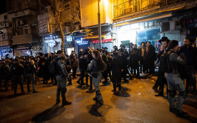 Police guard while Haredi men protest against a cellular shop in Jerusalem's Geula neighborhood, on January 15, 2023 (Yonatan Sindel/Flash90)
