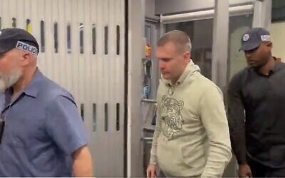 Modeling agent Shay Avital, center, is escorted off a plane at Ben Gurion Airport after being extradited from the Netherlands, January 3, 2022. (Twitter; used in accordance with Clause 27a of the Copyright Law)