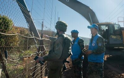 An Israeli soldier and UNIFIL troops inspect an IDF excavator working on the border with Lebanon, January 19, 2023. (Israel Defense Forces)