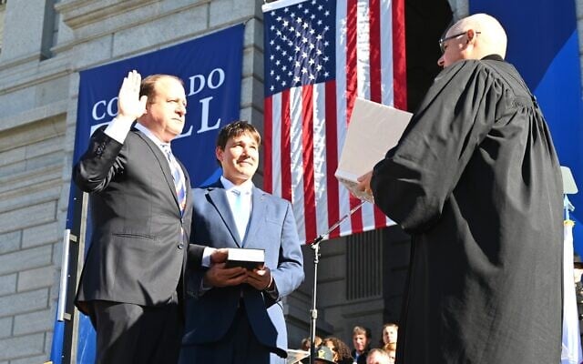 Brian Boatright, the chief justice of the Colorado Supreme Court, at right, swears in Gov. Jared Polis, on the left, while Polis's husband, Marlon Reis, holds a Hebrew bible, in Denver, Jan. 10, 2023. (Gov. Jared Polis Facebook page via JTA) Brian Boatright, the chief justice of the Colorado Supreme Court, at right, swears in Gov. Jared Polis, on the left, while Polis's husband, Marlon Reis, holds a Hebrew bible, in Denver, Jan. 10, 2023. (Gov. Jared Polis Facebook page via JTA)