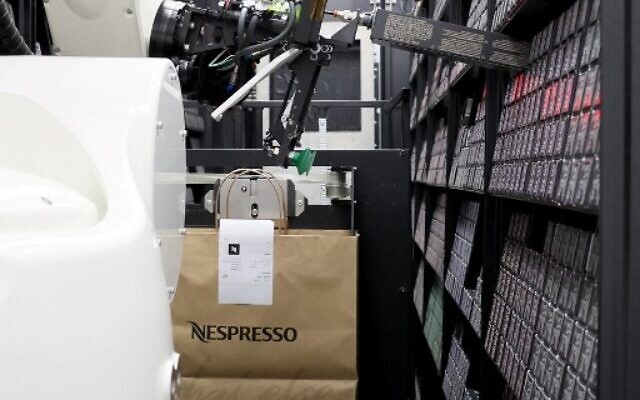 A robot prepares a bag of Nespresso coffee capsules ahead of its distribution to a customer, at the automated storeroom designed by the Israeli company 1MRobotics, in Tel Aviv, January 11, 2023. (JACK GUEZ/AFP) A robot prepares a bag of Nespresso coffee capsules ahead of its distribution to a customer, at the automated storeroom designed by the Israeli company 1MRobotics, in Tel Aviv, January 11, 2023. (JACK GUEZ/AFP)