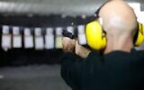 A man fires a pistol at an indoor shooting range during a qualification course in Katzrin in the Golan Heights on January 31, 2023. (Jalaa Marey/AFP)