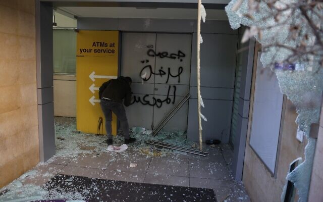 A potester sprays Arabic graffiti which reads "Depositors Outcry Association" as angry Lebanese vandalised banks in Beirut on February 16, 2023, one day after the Lebanese pound hit a record low against the dollar on the black market. (Joseph Eid/AFP) A potester sprays Arabic graffiti which reads "Depositors Outcry Association" as angry Lebanese vandalised banks in Beirut on February 16, 2023, one day after the Lebanese pound hit a record low against the dollar on the black market. (Joseph Eid/AFP)