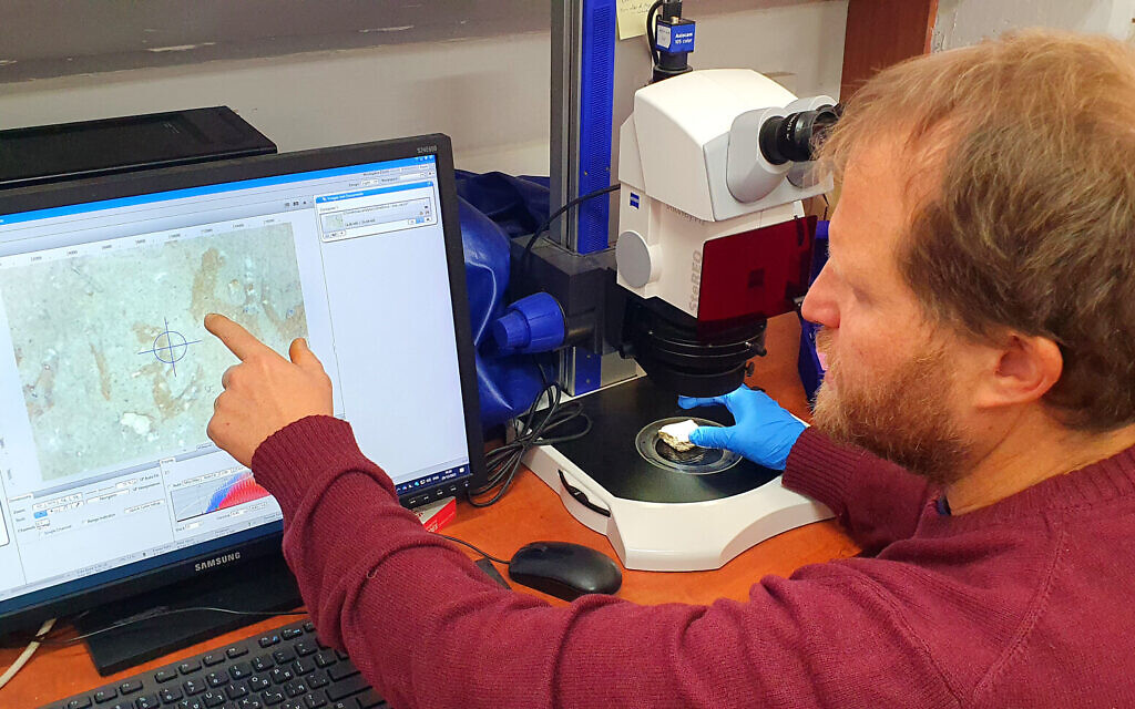 Experts examine the potsherd at the Israel Antiquities Authority's analytical lab, revealed on March 1 by the IAA. (Saar Ganon/IAA)