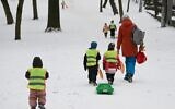 Young children pull a sledge as they walk up a slope through snow in the western Ukrainian city of Lviv on February 7, 2023, amid the Russian invasion of Ukraine. (Yuriy Dyachyshyn/AFP)