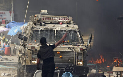 A Palestinian faces an Israeli military vehicle during a raid in the West Bank city of Nablus, on February 22, 2023. (Zain Jaafar / AFP)