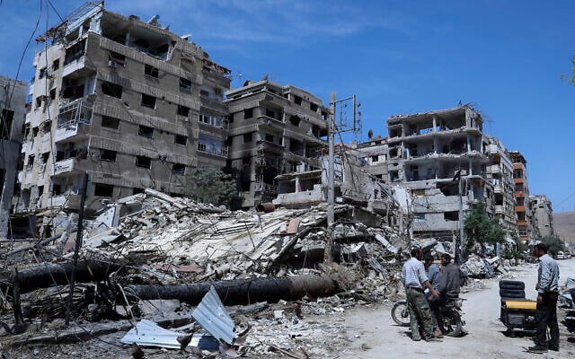 People stand in front of damaged buildings in the town of Douma, the site of a suspected chemical weapon attack, near Damascus, Syria, on April 16, 2018. (Hassan Ammar/AP) People stand in front of damaged buildings in the town of Douma, the site of a suspected chemical weapon attack, near Damascus, Syria, on April 16, 2018. (Hassan Ammar/AP)