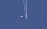 A large balloon drifts above the Kingstown, North Carolina area, with an airplane and its contrail seen below it. (Brian Branch via AP)