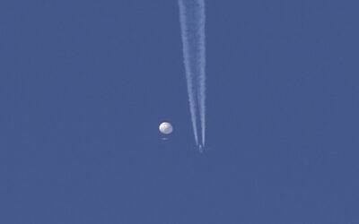 A large balloon drifts above the Kingstown, North Carolina area, with an airplane and its contrail seen below it. (Brian Branch via AP)