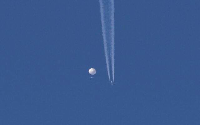 A large balloon drifts above the Kingstown, N.C. area, with an airplane and its contrail seen below it. (Brian Branch via AP)