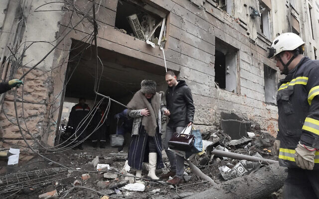 Illustrative: A man helps a woman to walk out from a residential building which was hit by a Russian rocket, in the city center of Kharkiv, Ukraine, February 5, 2023. (AP Photo/Andrii Marienko) Illustrative: A man helps a woman to walk out from a residential building which was hit by a Russian rocket, in the city center of Kharkiv, Ukraine, February 5, 2023. (AP Photo/Andrii Marienko)