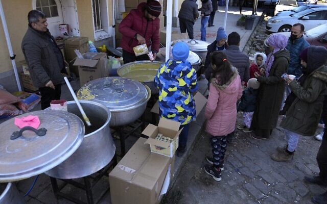 People wait to receive a hot meal, in Iskenderun city, southern Turkey, February 14, 2023. (Hussein Malla/AP)
