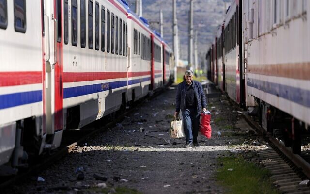 A man walks between trains used as shelters, in Iskenderun city, southern Turkey, February 14, 2023. (Hussein Malla/AP)