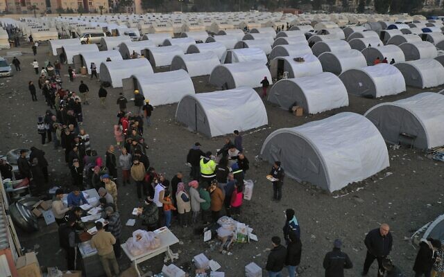 People who lost their houses in the devastating earthquake, line up to receive food at a makeshift camp, in Iskenderun city, southern Turkey, February 14, 2023. (Hussein Malla/AP)
