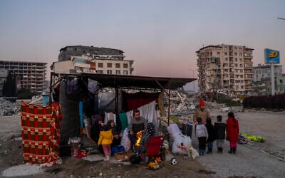 A family stays in a makeshift tent surrounded of buildings that were heavily affected during the earthquake in Antakya, southeastern Turkey, February 14, 2023. (Bernat Armangue/AP)