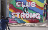 A television cameraman works near a tribute to the victims of a mass shooting at a gay nightclub painted on the side of a downtown commercial building Nov. 23, 2022, in Colorado Springs, Colo. (AP/David Zalubowski)