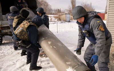 Ukrainian emergency services employees push the remains of an S-300 missile fired by Russian forces onto a truck in Kharkiv, Ukraine, on February 17, 2023. (AP Photo/Vadim Ghirda)