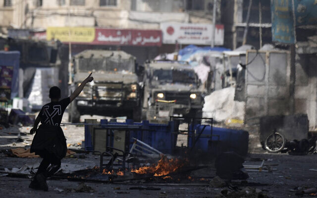 A Palestinian gestures to Israeli military vehicles during clashes in the West Bank city of Nablus, February 22, 2023. (AP Photo/Majdi Mohammed) A Palestinian gestures to Israeli military vehicles during clashes in the West Bank city of Nablus, February 22, 2023. (AP Photo/Majdi Mohammed)