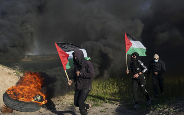 Palestinians wave flags and burn tires along the border fence between Israel and Gaza, Feb. 22, 2023. (AP Photo/Adel Hana) Palestinians wave flags and burn tires along the border fence between Israel and Gaza, Feb. 22, 2023. (AP Photo/Adel Hana)