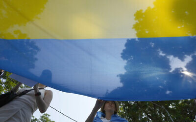 Ukrainian people living in Thailand hold Ukraine national flag during a rally to mark the one-year anniversary of Russia's invasion of Ukraine, in Bangkok, Thailand, February 24, 2023. (AP Photo/Salkchai Lalit)