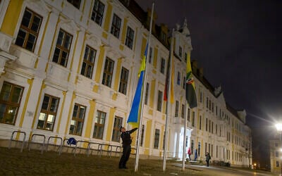A policeman raises the flag of Ukraine in front of the state parliament of Saxony-Anhalt in Magdeburg, Germany February 24, 2023. (Klaus-Dietmar Gabbert/dpa via AP)