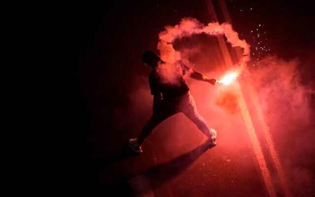 A man holds a flare at a protest in Tel Aviv against plans by the government to overhaul the judicial system, Feb. 25, 2023. (AP Photo/Ariel Schalit) A man holds a flare at a protest in Tel Aviv against plans by the government to overhaul the judicial system, Feb. 25, 2023. (AP Photo/Ariel Schalit)