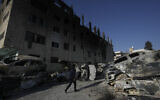 A Palestinian man walks past burned cars in the town of Huwara, near the West Bank city of Nablus, February 27, 2023. (AP Photo/Majdi Mohammed)