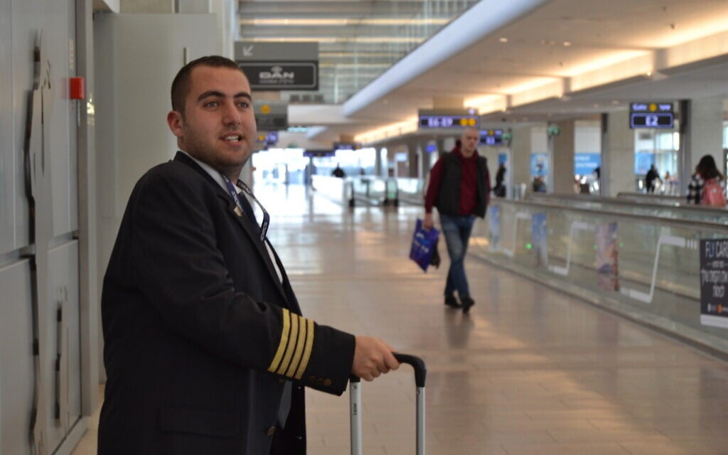Idan Fishslevich, a 22-year-old with high functioning ASD who was made a flight attendant for one day, poses for a picture at Ben Gurion Airport before boarding the plane, February 20, 2023. (Tobias Siegal/The Times of Israel)