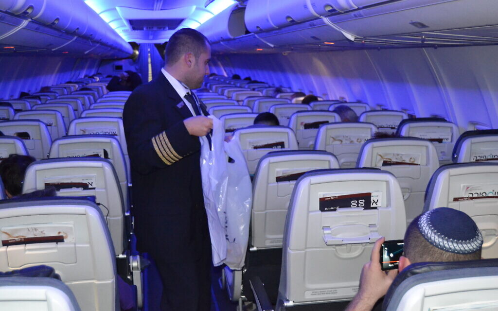 Idan Fishslevich, a 22-year-old with high functioning ASD who was made a flight attendant for one day, is seen serving passengers onboard flight LY383 from Tel Aviv Rome, February 20, 2023. (Tobias Siegal/The Times of Israel)