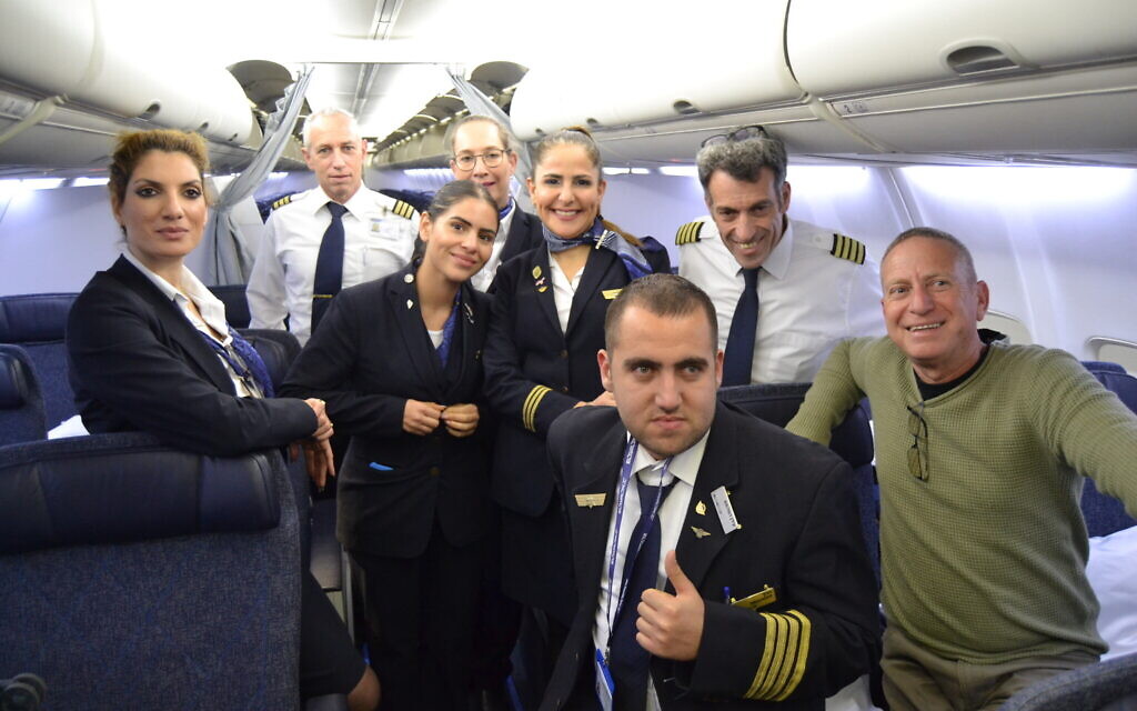 Idan Fishslevich, a 22-year-old with high functioning ASD who was made a flight attendant for one day, poses for a picture together with his father Amir and El Al's staff onboard El Al's flight LY383 to Rome, Italy, February 20, 2023. (Tobias Siegal/The Times of Israel)