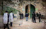 Illustrative: Ultra-Orthodox Jewish men, left, pray as as Israeli police officers guard the entrance to the Al Aqsa Mosque, in Jerusalem's Old City on April 19, 2022. (Yonatan Sindel/Flash90)