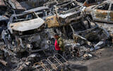 A Palestinian man walks between scorched cars in a scrapyard after a settler riot, in the town of Huwara, near the West Bank city of Nablus, February 27, 2023. (AP Photo/Ohad Zwigenberg)