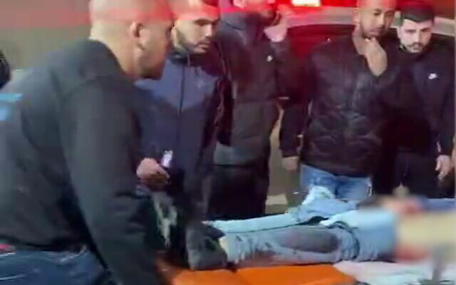 People look on as medics take two men who were shot in the northern town of Jadeidi-Makr to a hospital, February 19, 2023. (Video screenshot: Used in accordance with Clause 27a of the Copyright Law) People look on as medics take two men who were shot in the northern town of Jadeidi-Makr to a hospital, February 19, 2023. (Video screenshot: Used in accordance with Clause 27a of the Copyright Law)