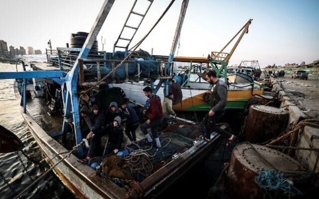 Palestinian fisherman Jihad al-Hissi and his sons work on their boat at the seaport in Gaza City on January 10, 2023. (MAHMUD HAMS/AFP) Palestinian fisherman Jihad al-Hissi and his sons work on their boat at the seaport in Gaza City on January 10, 2023. (MAHMUD HAMS/AFP)