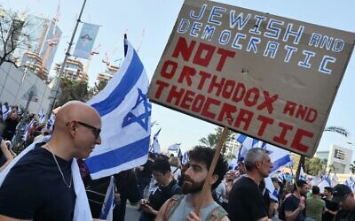 Protesters hold signs during a demonstration against the government's controversial justice reform bill in Tel Aviv on March 1, 2023. (Jack Guez/AFP)