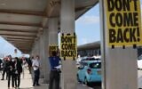 An anti-government protester sticks a poster with the slogan 'Don't Come Back' during a demonstration outside Ben Gurion Airport against the controversial judicial reform bill as Prime Minister Benjamin Netanyahu heads to Germany on an official visit on March 15, 2023. (AHMAD GHARABLI/AFP)