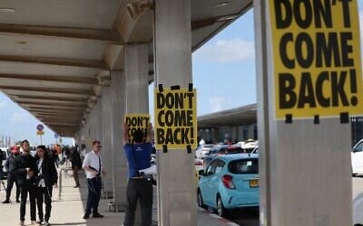 An anti-government protester sticks a poster with the slogan 'Don't Come Back' during a demonstration outside Ben Gurion Airport against the controversial judicial reform bill as Prime Minister Benjamin Netanyahu heads to Germany on an official visit on March 15, 2023. (AHMAD GHARABLI/AFP)
