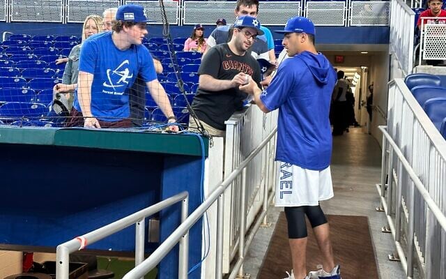 Lloyd Kaplan, center, gets an autograph from Team Israel player Matt Mervis at the World Baseball Classic in Miami, March 13, 2023. (Jacob Gurvis/ JTA)