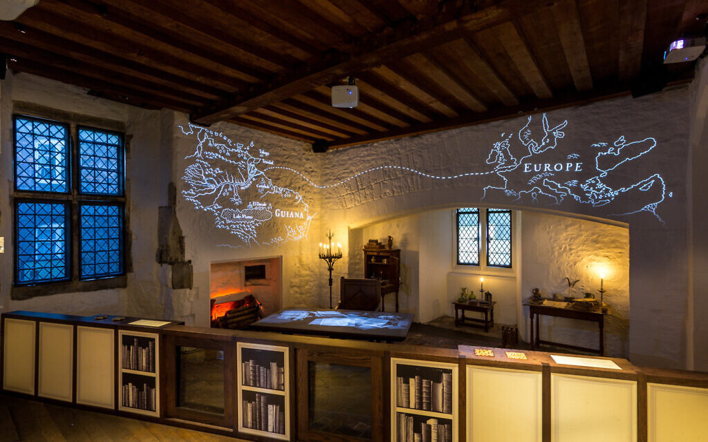 Sir Walter Raleigh's Study downstairs in the Bloody Tower at the Tower of London, showing a desk and walls with projections. (© Historic Royal Palaces)