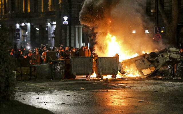 Protesters gather at a barricade with a burning police car, not far from the Georgian parliament building in Tbilisi, Georgia, March 9, 2023. (Zurab Tsertsvadze/AP)
