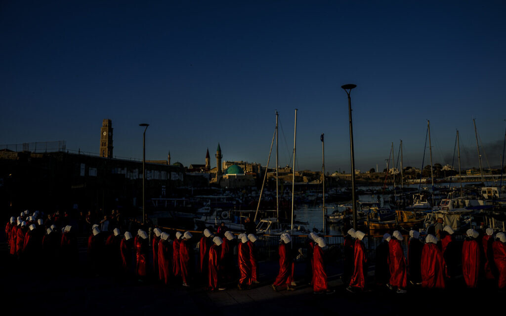 Protesters supporting women's rights dressed as characters from "The Handmaid's Tale" TV series attend a protest against the government's plans to overhaul the judicial system in the old port of Acre in northern Israel, March 16, 2023. (AP/Ariel Schalit)