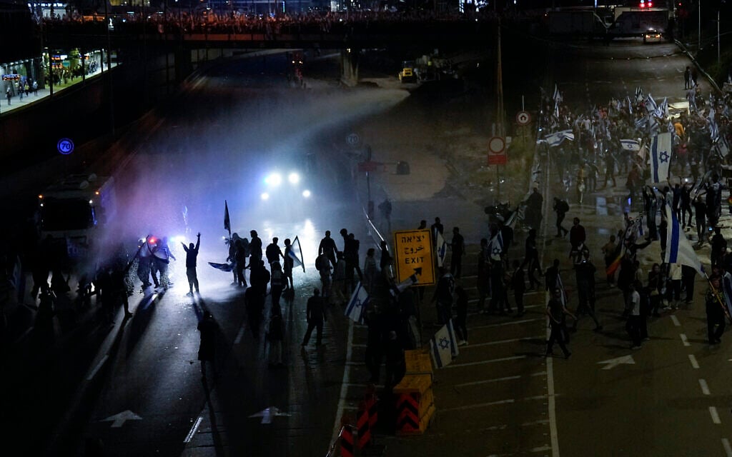 Israeli police use a water cannon to disperse Israelis blocking a highway during a protest against plans by Prime Minister Benjamin Netanyahu's government to overhaul the judicial system in Tel Aviv, Israel, March 25, 2023. (AP Photo/Ariel Schalit)