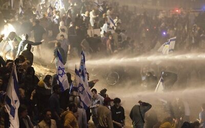 Israeli police use a water cannon to disperse demonstrators blocking a highway during a protest against plans by Prime Minister Benjamin Netanyahu's government to overhaul the judicial system in Tel Aviv, Israel, March 27, 2023. (AP Photo/ Oren Ziv)