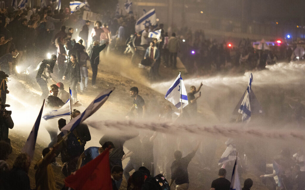 Police use a water cannon to disperse demonstrators blocking a highway during a protest against plans by Prime Minister Benjamin Netanyahu's government to overhaul the judicial system, in Tel Aviv, Israel, Monday, March 27, 2023. (AP Photo/Oren Ziv) Police use a water cannon to disperse demonstrators blocking a highway during a protest against plans by Prime Minister Benjamin Netanyahu's government to overhaul the judicial system, in Tel Aviv, Israel, Monday, March 27, 2023. (AP Photo/Oren Ziv)