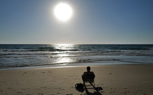 Enjoying the last hours of a vey hot day at Poleg beach in Netanya on July 28, 2022. (Michael Giladi/Flash90) Enjoying the last hours of a vey hot day at Poleg beach in Netanya on July 28, 2022. (Michael Giladi/Flash90)