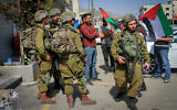 Palestinians confront Israeli soldiers while waving Palestinian flags in the center of the town of Huwara, in the West Bank, March 2, 2023. (Nasser Ishtayeh/Flash90)